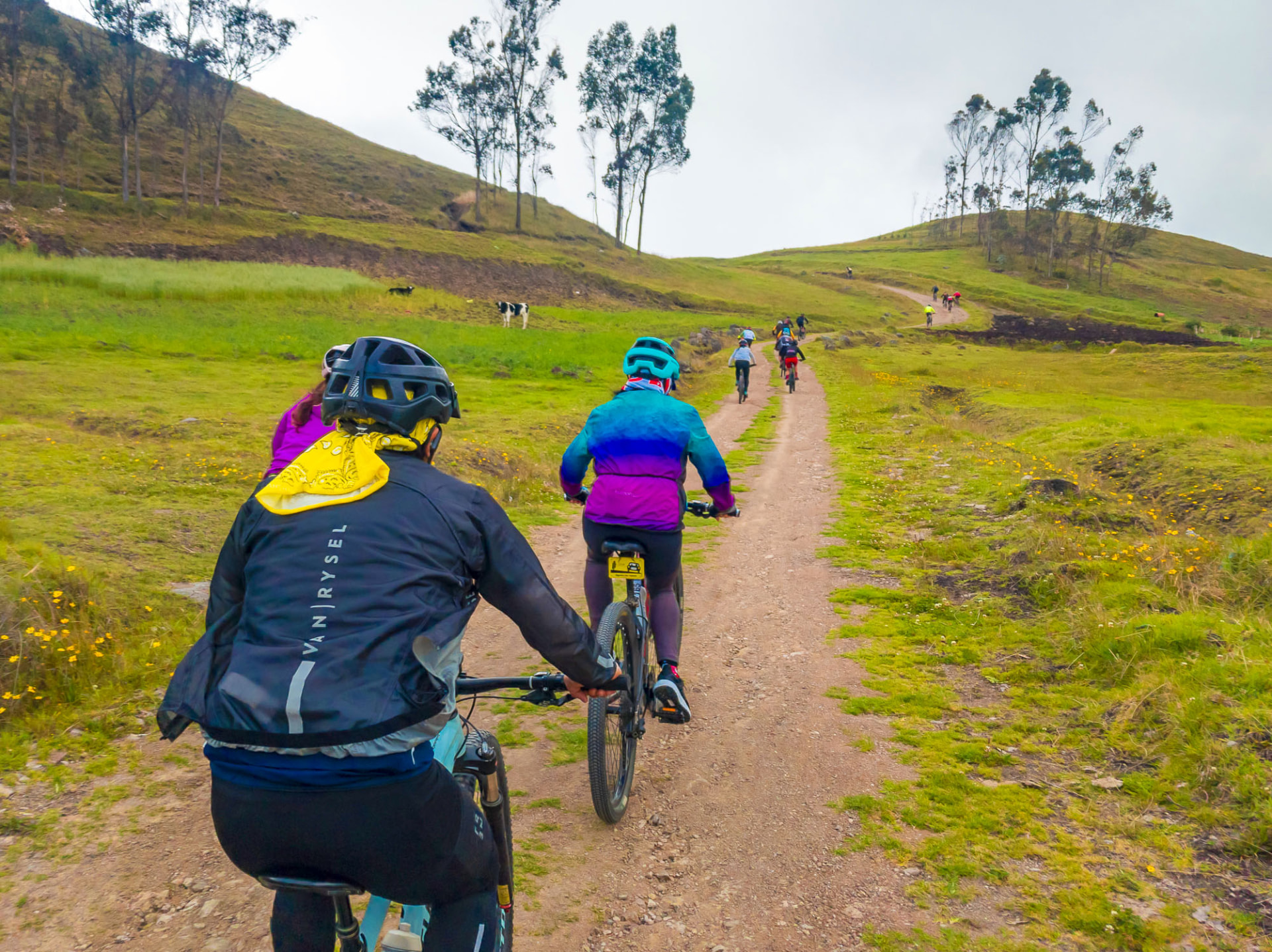 Grupo de ciclistas subiendo un sendero de tierra entre lomas verdes
