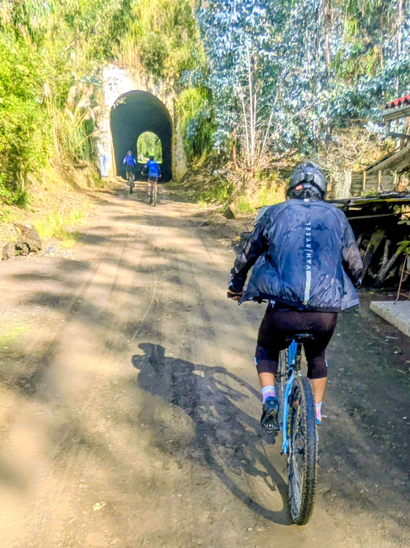 Ciclistas entrando a un túnel ferroviario rodeado de vegetación
