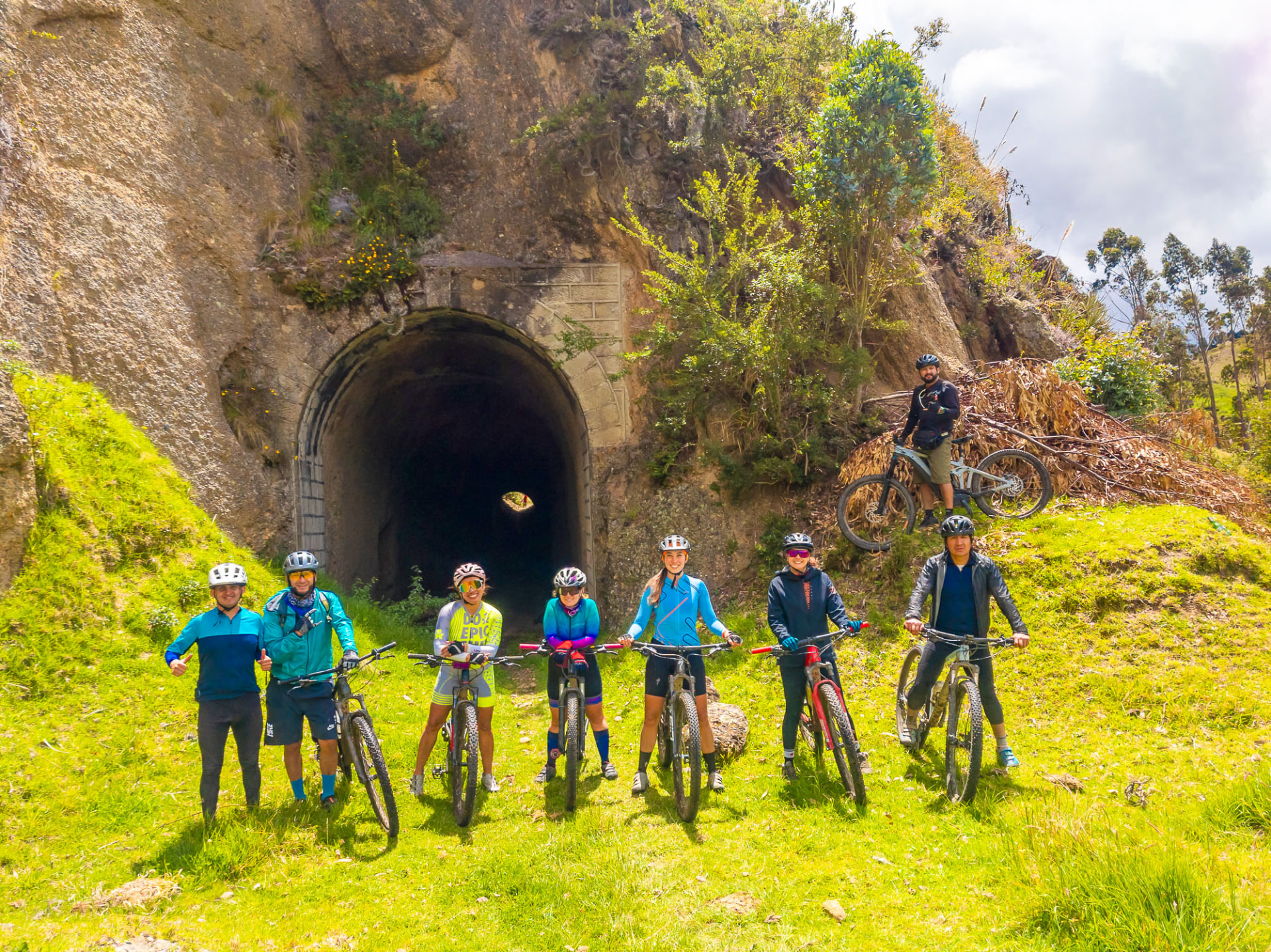 Ciclistas posando frente a un túnel de piedra de la antigua vía férrea