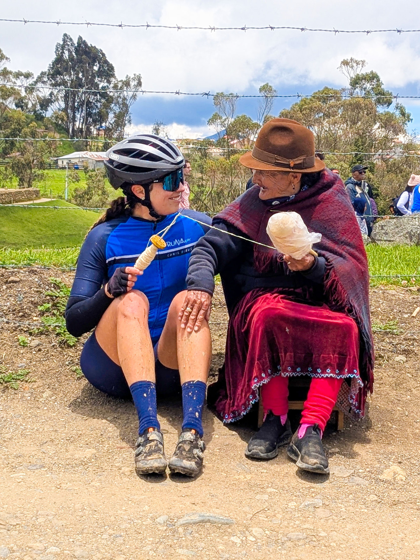 Ciclista conversando con una mujer cañari que hila lana